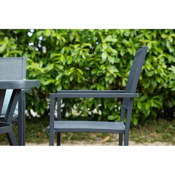 Garden Impressions Stapelstuhl Moon - Aluminium, Schwarz/Anthrazit, B x T x H: 59 x 55 x 91 cm - Dunkelgrauer Metall-Gartenstuhl mit Netzgewebe-Sitz und -Rückenlehne, neben einem passenden Tisch.