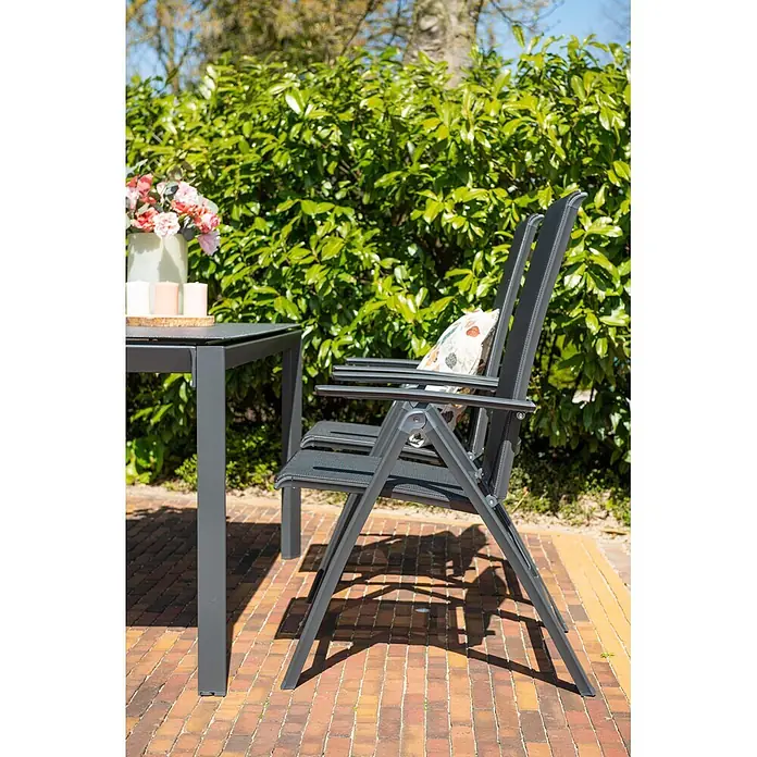 Garden Impressions Garten-Positionssessel Gala - Aluminium, Klappbar, Schwarz/Anthrazit, B x T x H: 61 x 75 x 108 cm - Dunkelgraues Outdoor-Essgruppe mit rechteckigem Tisch und zwei Klappstühlen auf einer Ziegelterrasse.