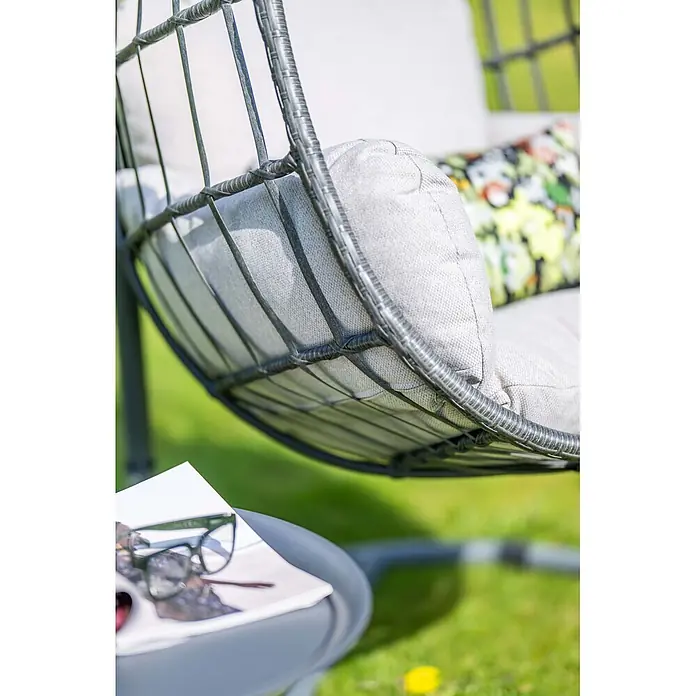 Garden Impressions Hängesessel Fargo - L x B x H: 92 x 79 x 198 cm, Metall, Schwarz/Grau - Dunkelgrauer Korbschaukelstuhl mit hellgrauen Kissen, im Freien mit Beistelltisch und Lesebrille.