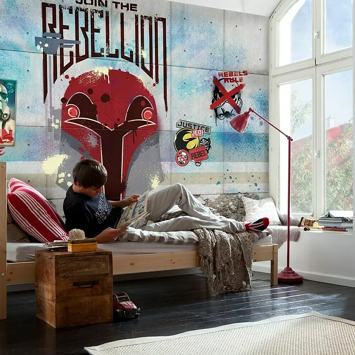 Komar Star Wars Fototapete Rebels Wall - 8 -tlg., B x H: 368 x 254 cm, Papier - Ein Junge liest in einem thematisch gestalteten Schlafzimmer mit Star Wars-Wandbild und roter Lampe.