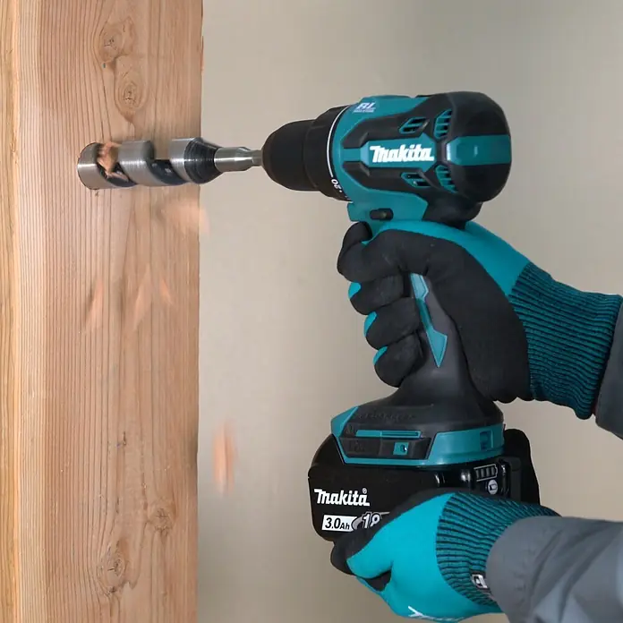 Makita LXT 18V Akku-Bohrschrauber DDF490Z - 18 V, Ohne Akku, 50 Nm - Türkis-schwarzer Makita Akkubohrschrauber (3.0Ah 18V) bohrt mit einem Holzbohrer in einen Holzbalken; Späne fliegen.