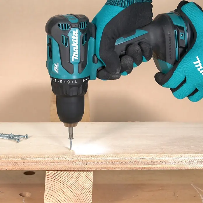 Makita LXT 18V Akku-Bohrschrauber DDF490Z - 18 V, Ohne Akku, 50 Nm - Eine Person mit türkis-schwarzen Handschuhen verwendet einen schwarz-türkisen Makita-Bohrschrauber, um eine Schraube in Holz zu drehen.