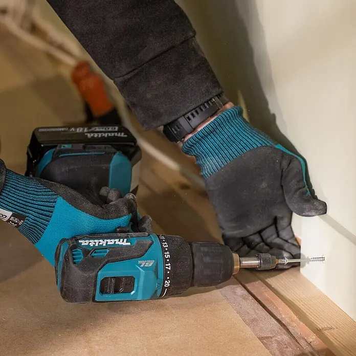 Makita LXT 18V Akku-Bohrschrauber DDF490Z - 18 V, Ohne Akku, 50 Nm - Eine Person mit Handschuhen verwendet einen türkis-schwarzen Makita Akku-Bohrschrauber, um eine Schraube in eine helle Leiste zu drehen.