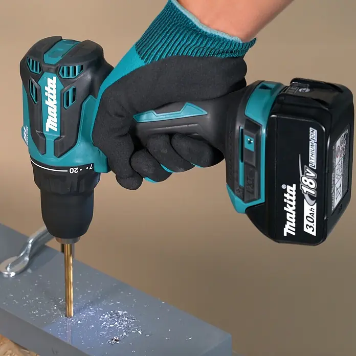 Makita LXT 18V Akku-Bohrschrauber DDF490Z - 18 V, Ohne Akku, 50 Nm - Türkis-schwarzer Makita Akku-Bohrschrauber, von behandschuhter Hand gehalten, bohrt in graue Oberfläche.