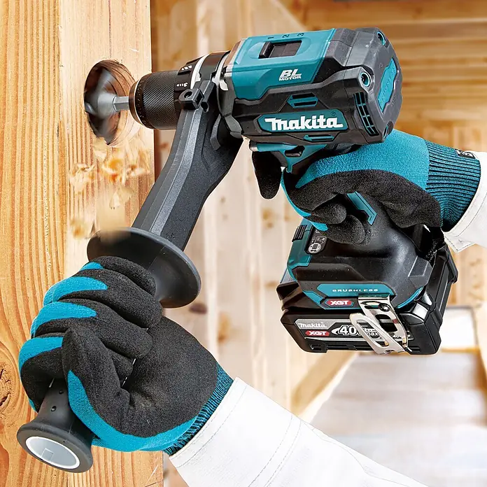 Makita XGT 40V max. Akku-Bohrschrauber DF003G - 40 V, Ohne Akku, 150 Nm - Eine Person bohrt mit einem türkis-schwarzen Makita Akku-Bohrschrauber und einem XGT 40V Akku ein Loch in einen Holzbalken, wobei Späne entstehen.