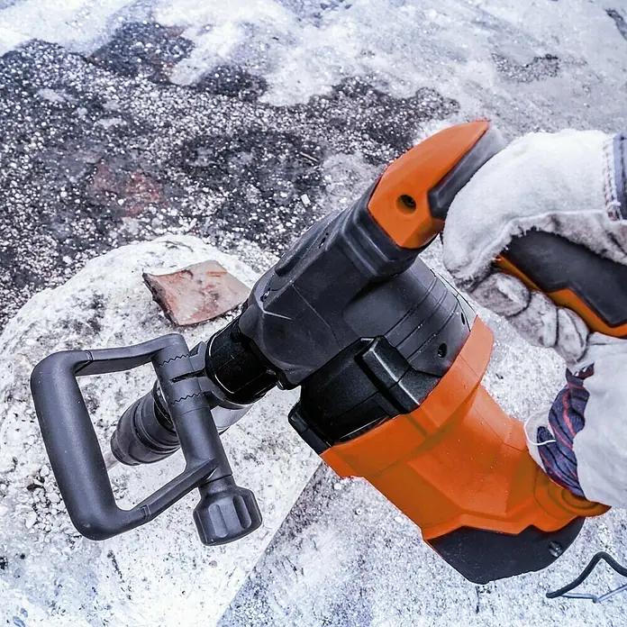 Toolson PRO Martillo demoledor HM 27 MAX - 1.500 W, 32 J, Alojamiento SDS-MAX - Primer plano de un martillo neumático con cuerpo naranja y mango negro, sobre una superficie blanca.