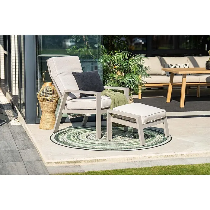 Garden Impressions Garten-Positionssessel Max - 1 Stk., Aluminium, Taupe, B x T x H: 78 x 72 x 107 cm - Hellgrauer Outdoor-Loungesessel mit passendem Ottoman und hellen Kissen, auf einer Terrasse mit grünem Rundteppich.