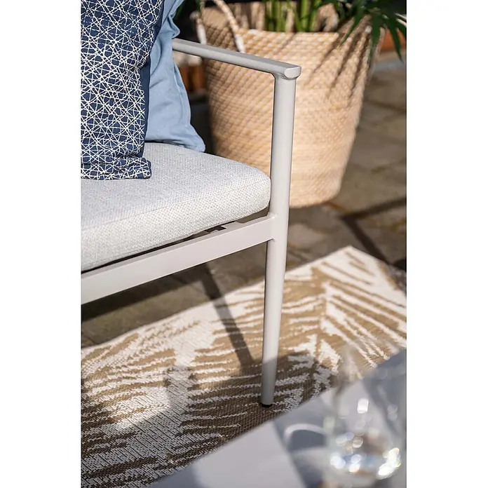 Garden Impressions Loungemöbel-Set Morella - 4 -tlg., Aluminium, Weiß - Nahaufnahme eines hellgrauen Outdoor-Stuhls mit grauem Kissen und blauen Zierkissen auf einem Outdoorteppich.