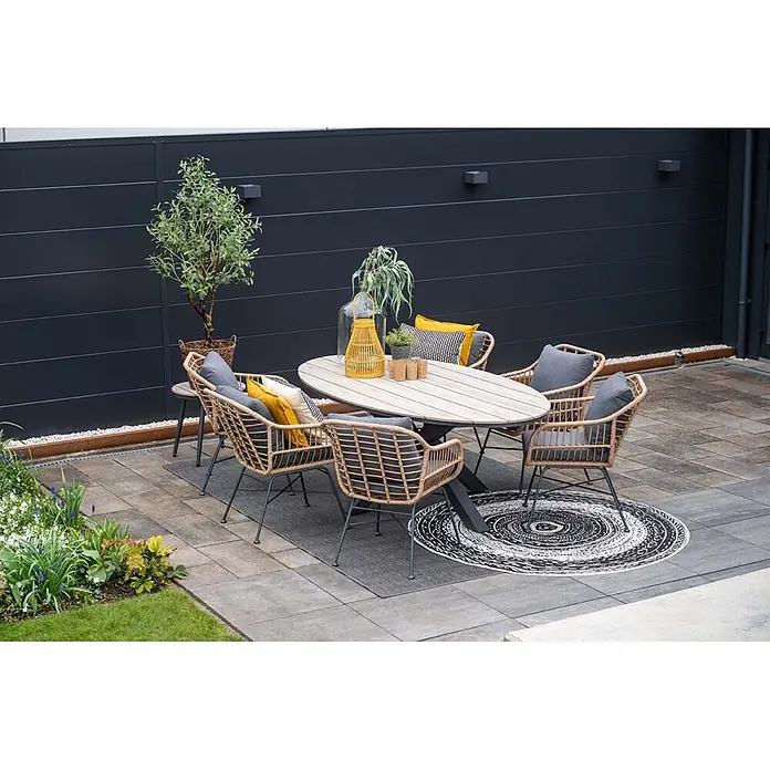 Garden Impressions Gartensessel Margriet - 1 Stk., Stahl, Polyester, Stapelbar, Schwarz/Grau, B x T x H: 69,5 x 91 x 59 cm - Garten-Essgruppe mit ovalem Holztisch und sechs Korbstühlen mit grauen Kissen, auf einer Terrasse mit zwei Teppichen.