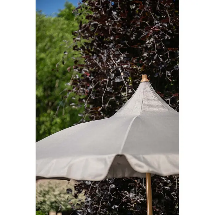 Garden Impressions Marktschirm rund Aloha - Taupe, Durchmesser Bespannung: 200 cm - Hellbeiger Gartenschirm mit Holzstange und braunem Knauf, inmitten üppigen Grüns.