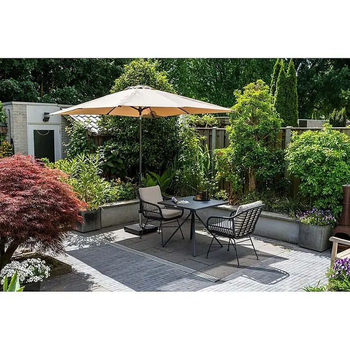 Garden Impressions Balkonschirm Lotus - Taupe, Quadratisch, Bespannungsmaß (L x B): 250 x 250 cm - Outdoor-Essgruppe mit dunklem Metalltisch, dunklen Korbstühlen mit hellen Kissen und beigem Sonnenschirm auf gepflasterter Terrasse.