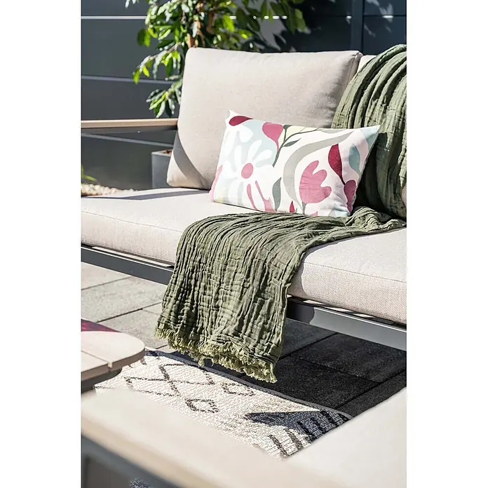 Garden Impressions Loungemöbel-Set Ricca - 4 -tlg., Aluminium, Grau/Schwarz - Ein Outdoor-Sofa mit beigen Kissen, einem Blumenmuster-Kissen und einer zerknitterten grünen Decke darauf.
