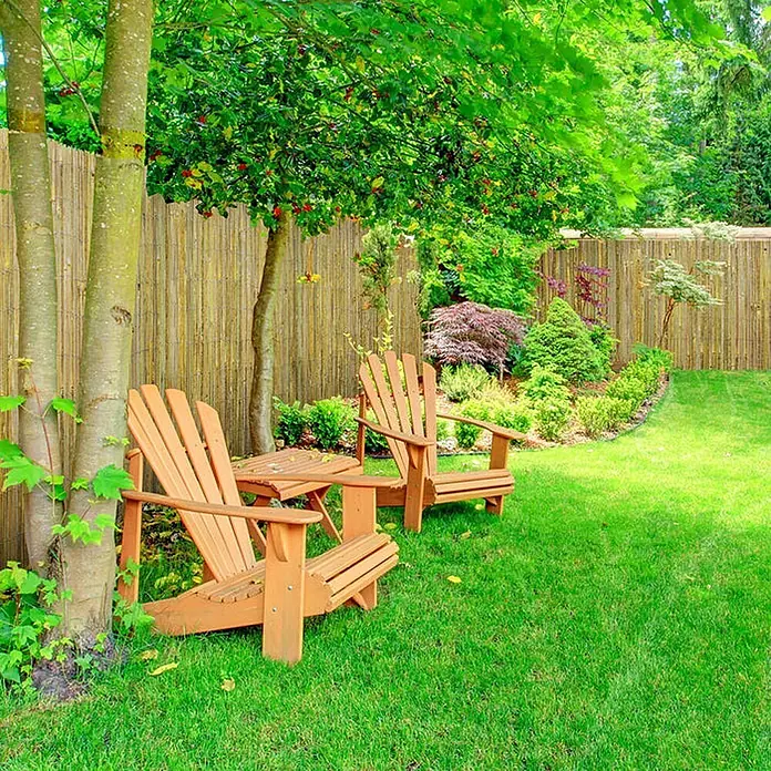 Floordirekt Sichtschutzelement Bambus Brasil - B x H: 200 x 2 cm, Naturmaterialien, Beige - Zwei hellbraune Adirondack-Stühle aus Holz mit passendem Beistelltisch in einem idyllischen Garten.