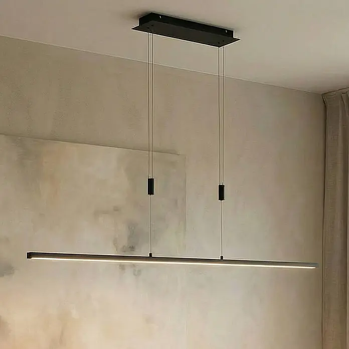 Lindby Pendelleuchte Arneja - L x B x H: 120 x 3,5 x 2 cm, schwarz, Schwarz matt - Eine lange, schlanke schwarze lineare Pendelleuchte mit beleuchtetem Streifen, an dünnen Drähten von der Decke eines modernen Raumes hängend.