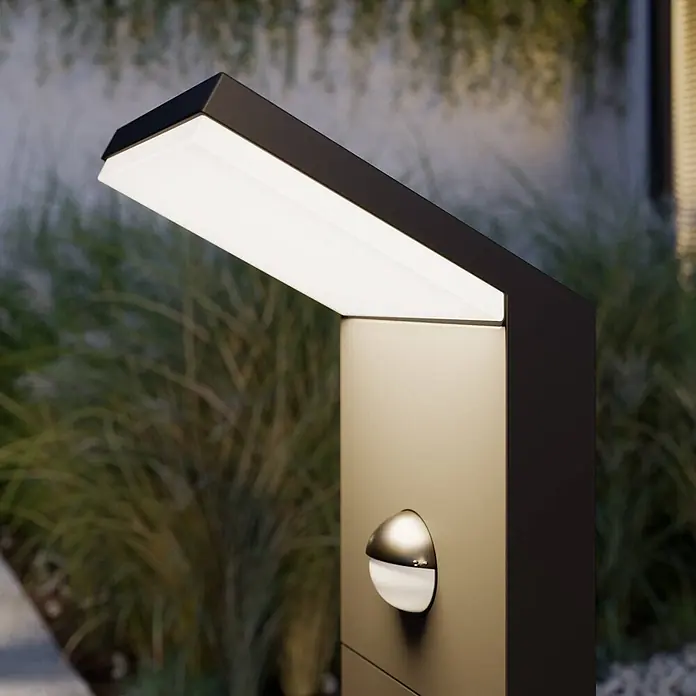 Lucande Außenlaterne Nevio -  - Moderne dunkle Außenleuchte mit angewinkelter LED-Blende und sphärischem Sensor, im Garten platziert.