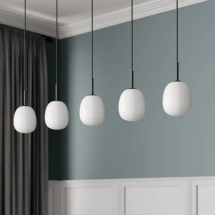 Lindby Pendelleuchte Etiena - L x B x H: 116 x 13 x 15 cm, opalweiß, Schwarz matt, G9 - Fünf moderne Pendelleuchten mit weißen, ovalen Glasschirmen und schwarzen Aufhängungen in einem modernen Raum.