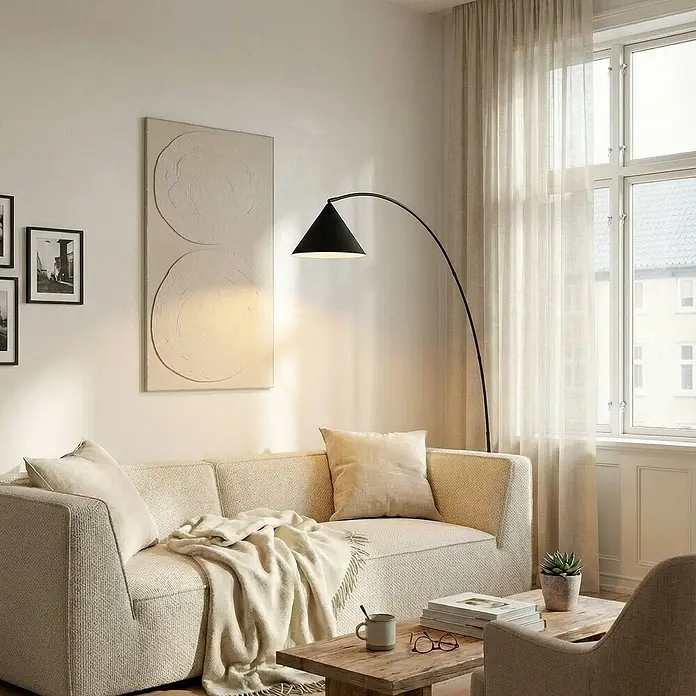 Lindby Stehleuchte Triangolo - Höhe: 195 cm, schwarz, schwarz, E27 - Eine elegante schwarze Bogenstehlampe mit konischem Schirm beleuchtet ein modernes Wohnzimmer neben einem hellen Sofa.