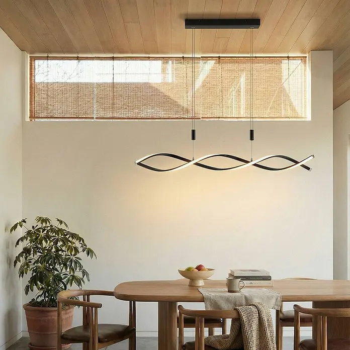Lindby Pendelleuchte Welina - L x B x H: 107 x 10 x 200 cm, schwarz, Schwarz matt - Moderne schwarze wellenförmige LED-Pendelleuchte über einem Holzesstisch.