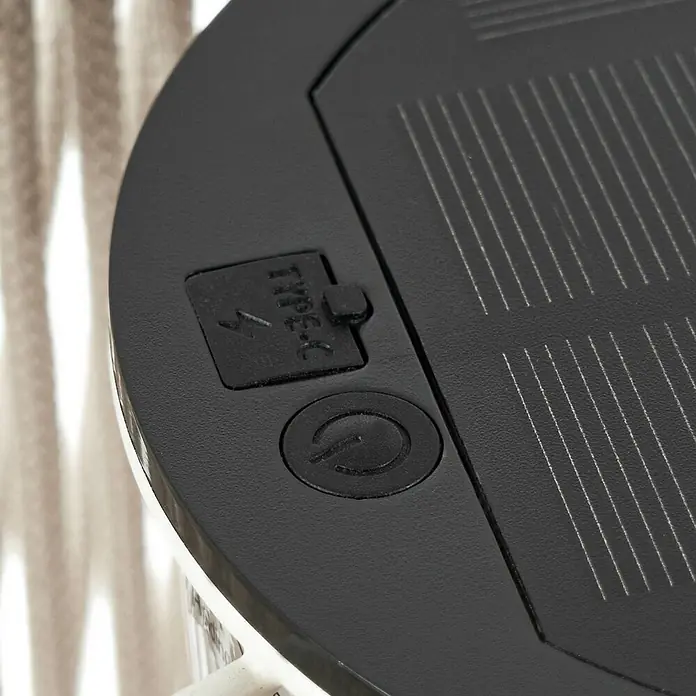 Lindby Außenwand- & Deckenleuchte Austas - creme / amber, IP54 - Obere Ansicht eines schwarzen Geräts mit Solarpanel, Type-C-Anschluss und Ein-/Ausschalter. Das Solarpanel weist feine weiße Linien auf.