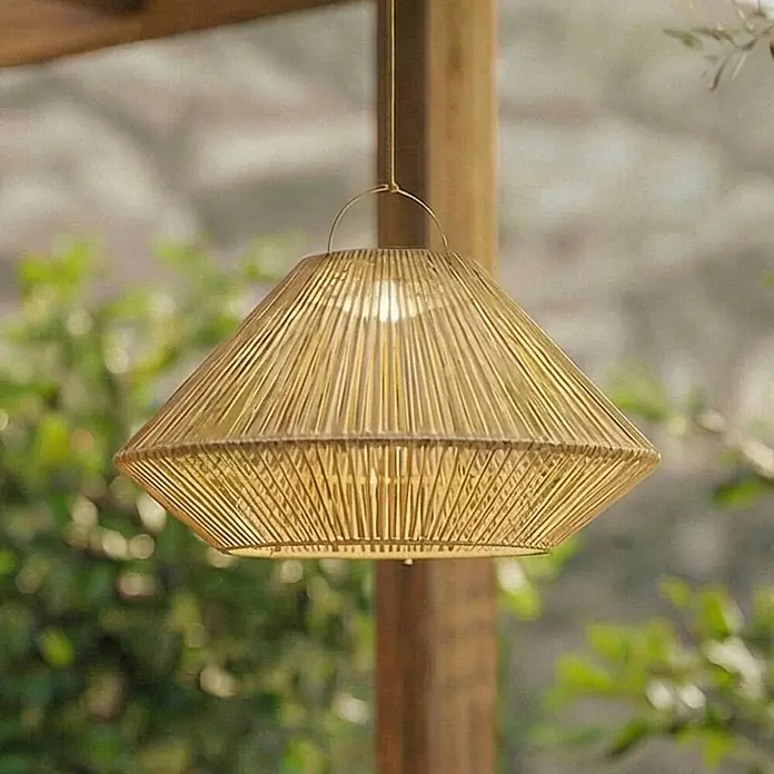 Lindby Außenwand- & Deckenleuchte Austas - creme / amber, IP54 - Eine beleuchtete goldene Hängelampe mit geflochtenem Schirm, im Freien hängend.