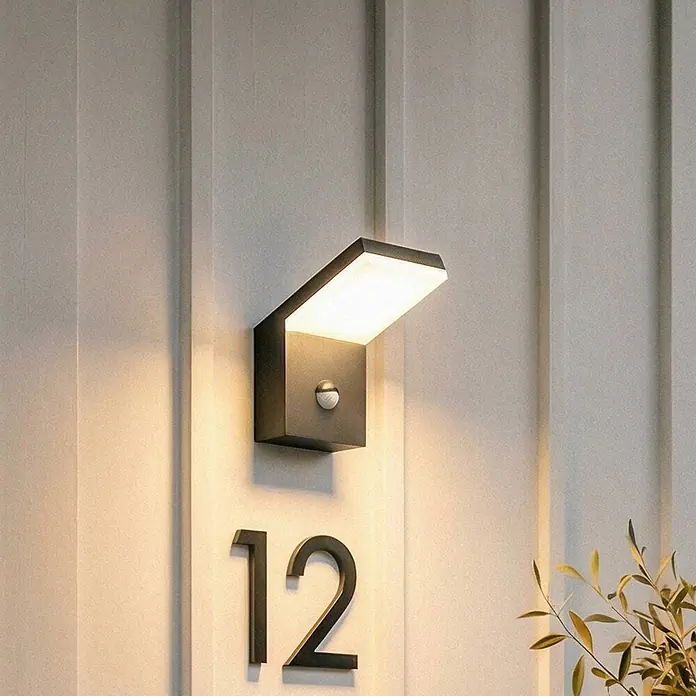 Arcchio Außenwandleuchte Yolena - schwarz, IP54 - Anthrazitfarbene Außenwandleuchte mit schrägem Design und integriertem Bewegungsmelder, beleuchtet Hausnummern an einer Wand.