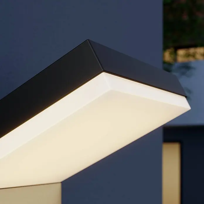 Arcchio Außenwandleuchte Yolena - schwarz, IP54 - Schwarze Wandleuchte mit leuchtendem, rechteckigem Diffusor, an dunkler Wand montiert.