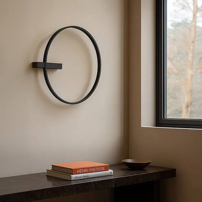 Lucande Deckenleuchte Isalin - schwarz - Schwarze minimalistische runde Wandleuchte an einer hellen Wand über einem dunklen Konsolentisch montiert.