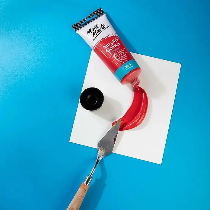 Mont Marte Acrylfarbe Signature - Brillantrot, 75 ml, Tube - Mont Marte rote Acrylfarbtube, Farbe, Spachtel und Kappe auf weißem Papier.