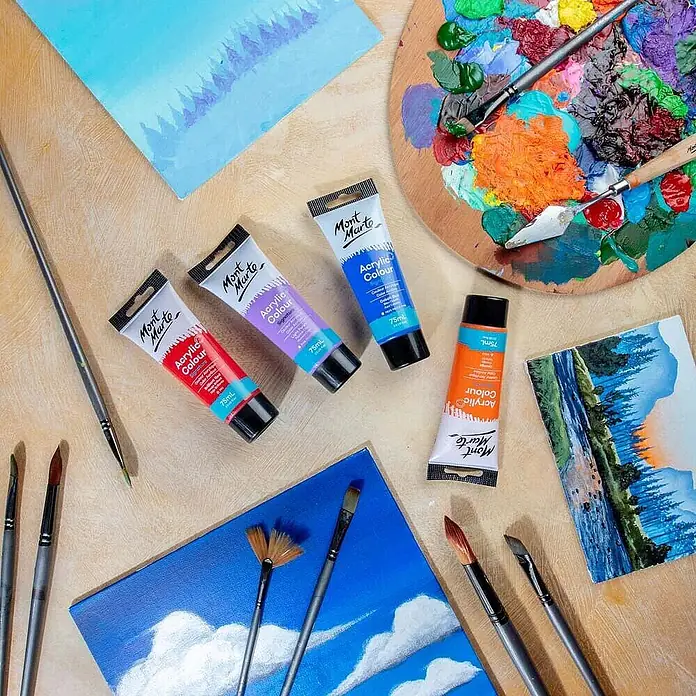 Mont Marte Acrylfarbe Signature - Brillantrot, 75 ml, Tube - Mont Marte Acrylfarben-Tuben in Rot, Lila, Blau und Orange, umgeben von Pinseln, einer farbigen Palette und unfertigen Acrylbildern.