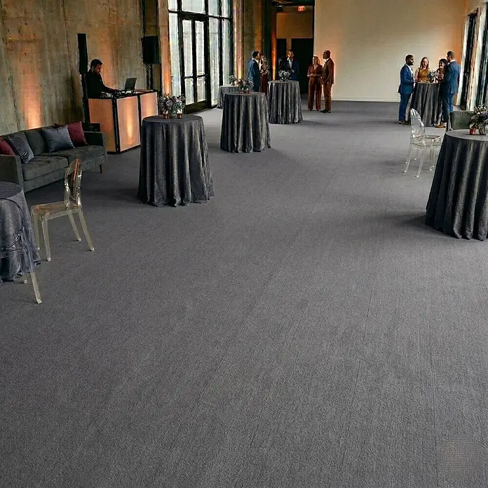 Floordirekt Teppichboden Meterware Sintra - für Messe & Events - Grau - 100 x 350 cm - Breite: 100 cm, Flachgewebe, Polypropylen, Grau - Texturierter grauer Teppich bedeckt den Boden eines großen Veranstaltungsraums, passt zu dunklen Möbeln und dient als neutrale Basis für Gäste.