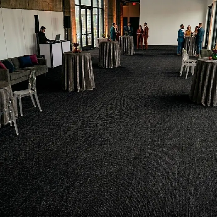Floordirekt Teppichboden Meterware Sintra - für Messe & Events - Schwarz - 200 x 100 cm - Breite: 200 cm, Flachgewebe, Polypropylen, Schwarz - Schwarze, gemusterte Teppichfliesen bedecken den Boden eines großen Veranstaltungsraums mit Lounge- und Stehtischen.