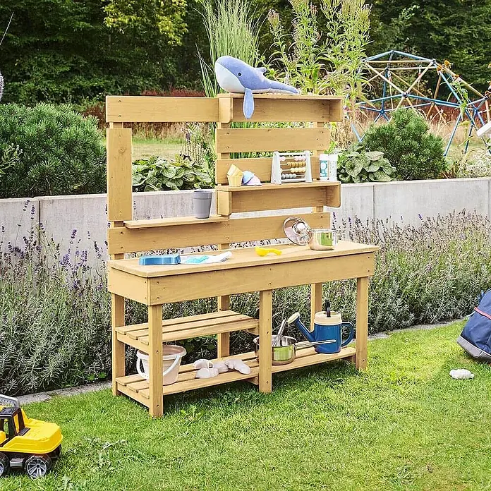 Home Deluxe Matschküche MANDU - Holz, Natur - Helle Holzküche für den Außenbereich mit Regalen, Theke und Spielzubehör in Gartenumgebung.