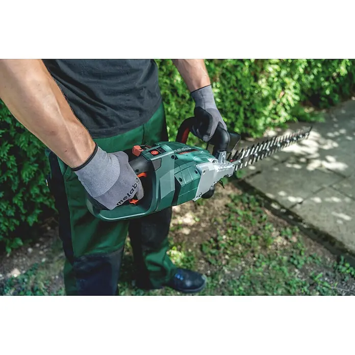 Metabo CAS 18V Akku-Heckenschere HS 18 LTX BL 75 - 18 V, Ohne Akku, Schnittlänge: 70 cm - Person hält eine grün-schwarze Metabo Heckenschere, bereit für den Garteneinsatz.