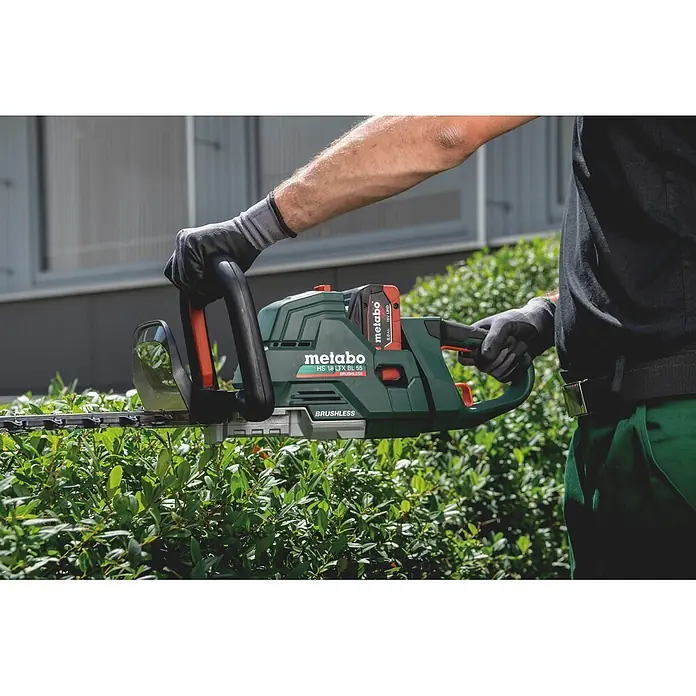 Metabo CAS 18V Akku-Heckenschere HS 18 LTX BL 75 - 18 V, Ohne Akku, Schnittlänge: 70 cm - Person schneidet eine grüne Hecke mit einer dunkelgrünen Metabo Akku-Heckenschere mit roten Akzenten und Akkupack.