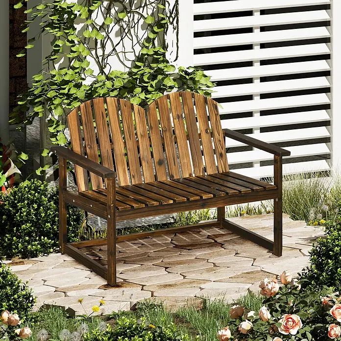 Outsunny Gartenbank - Tannenholz, Verkohlt - Eine dunkelbraune Holzgartenbank für zwei Personen mit Lattenrost, auf einer Steinterrasse inmitten von Grün und Blumen.
