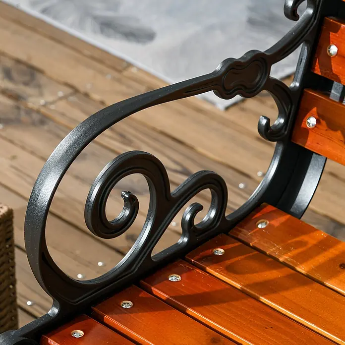 Furnicato Gartenbank - Aluminium/Holz, Teak - Detailaufnahme einer Parkbank mit schwarzer, verzierter Metallarmlehne und glänzenden braunen Holzlatten.