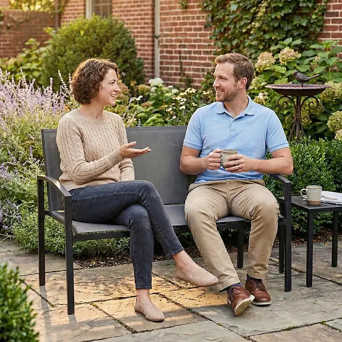 Outsunny Gartenbank - B x T x H: 66 x 66 x 80 cm, Metall, Netzstoff, Grau - Zwei Personen genießen eine dunkelgraue Metallgartenbank und einen Beistelltisch auf einer Terrasse und unterhalten sich bei Kaffee.