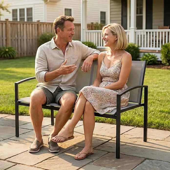 Outsunny Gartenbank - B x T x H: 66 x 66 x 80 cm, Metall, Netzstoff, Grau - Ein Paar sitzt auf einer Gartenbank mit schwarzem Rahmen und grauer Netzbespannung auf einer sonnigen Terrasse im Freien.