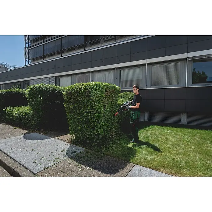Metabo CAS 18V Akku-Heckenschere HS 18 LTX BL 65 - 18 V, Ohne Akku, Schnittlänge: 60 cm - Ein Mann trimmt eine Hecke mit einer schwarzen und orangefarbenen Heckenschere.