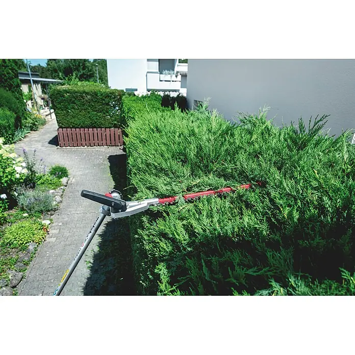 Metabo Heckenscheren-Aufsatz - Passend für: Akku-Multifunktionsantrieb MA 36-18 LTX BL Q - Eine Heckenschere mit roten Klingen und silbernem Kopf trimmt eine dichte grüne Hecke.