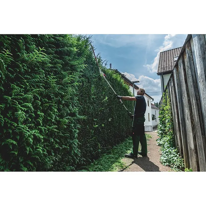 Metabo Heckenscheren-Aufsatz - Passend für: Akku-Multifunktionsantrieb MA 36-18 LTX BL Q - Mann schneidet eine hohe Hecke mit einer Langstiel-Heckenschere.