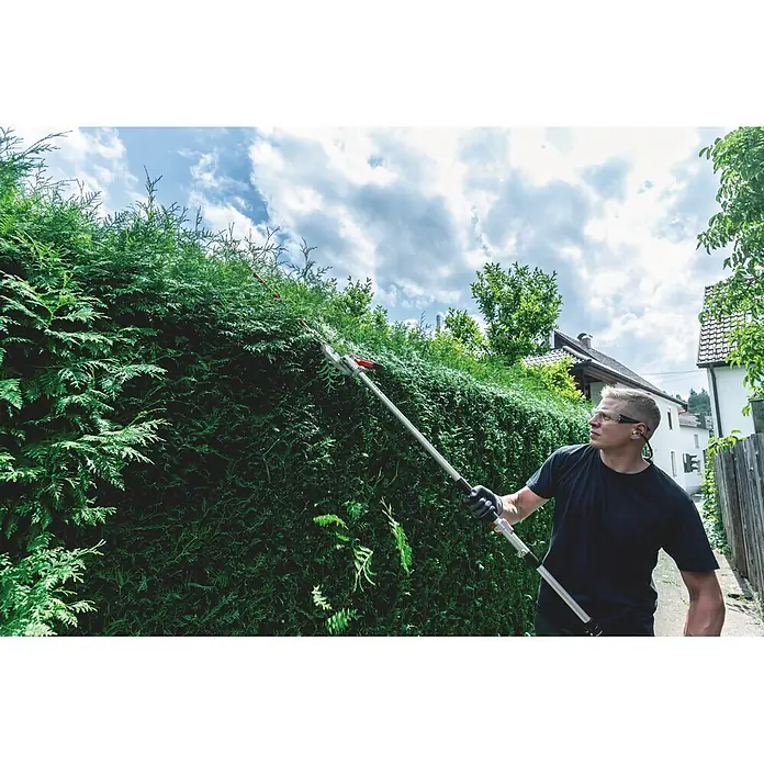 Metabo Heckenscheren-Aufsatz - Passend für: Akku-Multifunktionsantrieb MA 36-18 LTX BL Q - Mann schneidet eine hohe Hecke mit einer silber-roten Langstiel-Heckenschere.
