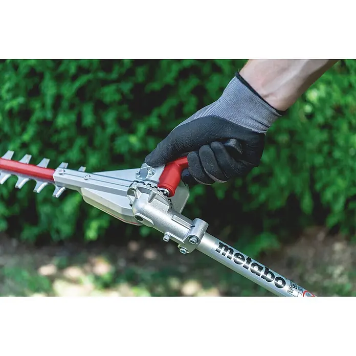 Metabo Heckenscheren-Aufsatz - Passend für: Akku-Multifunktionsantrieb MA 36-18 LTX BL Q - Behändigte Hand bedient eine silberne Metabo Heckenschere mit roten Akzenten.