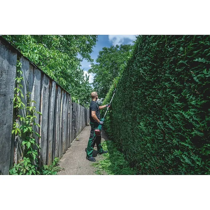 Metabo Heckenscheren-Aufsatz - Passend für: Akku-Multifunktionsantrieb MA 36-18 LTX BL Q - Mann trimmt eine hohe Hecke mit einer grün-silbernen Langstiel-Heckenschere.