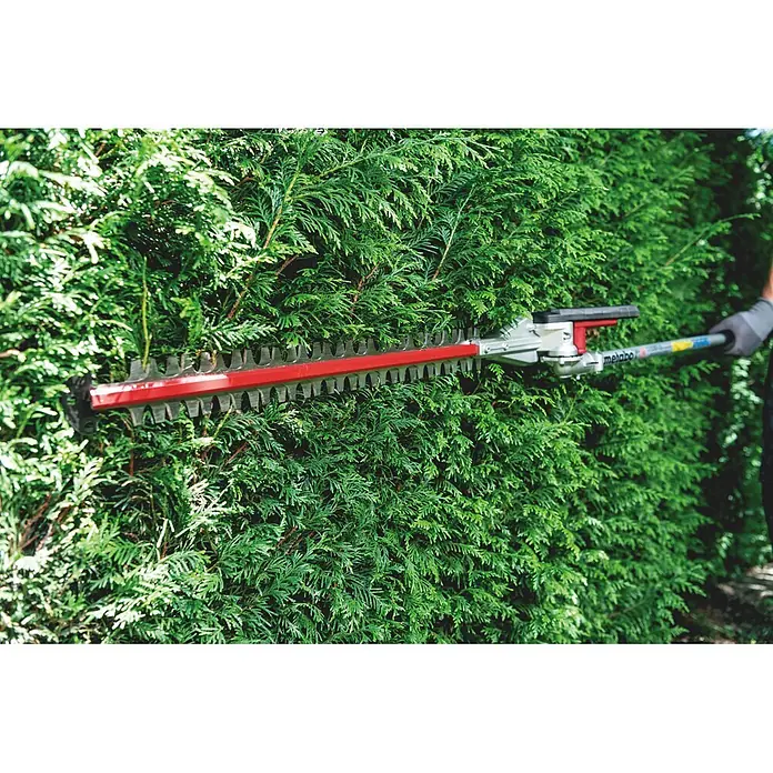 Metabo Heckenscheren-Aufsatz - Passend für: Akku-Multifunktionsantrieb MA 36-18 LTX BL Q - Metabo Heckenschere mit roter Klinge und silbernem Mechanismus schneidet eine grüne Hecke, gehalten von einer behandschuhten Hand.