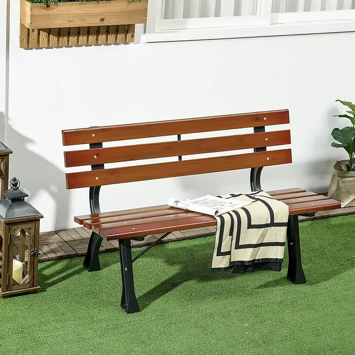 Outsunny Gartenbank - B x T x H: 57 x 57 x 70 cm, Gusseisen, Tannenholz, Kaffee - Braune Holzgartenbank mit dunklem Metallgestell, draußen mit Decke und Zeitung platziert.