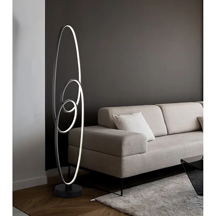 Globo LED-Deckenfluter Spira - 39 W, Höhe: 1.220 mm - Moderne schwarze Stehlampe mit verschlungenen ovalen LED-Lichtern, neben einem Sofa im Wohnzimmer.
