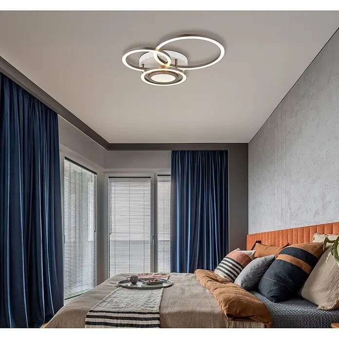 Globo Plafón LED Randell - 40 W, L x An x Al: 490 x 390 x 100 mm - Lámpara de techo geométrica moderna con anillos iluminados entrelazados, acabado plateado/gris, instalada en un dormitorio.