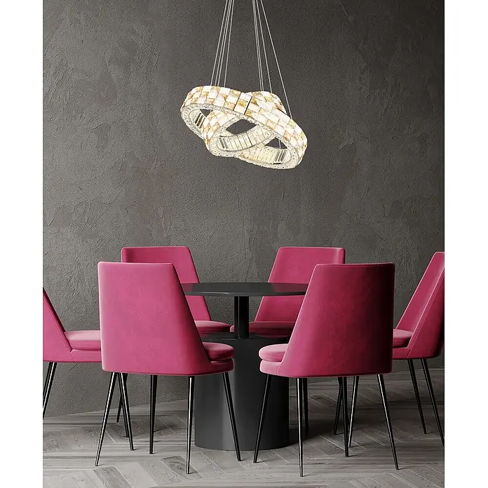Globo LED-Pendelleuchte rund Lidia - 55 W, Ø x H: 61 x 120 cm - Ein aufwendiger Kronleuchter aus ineinandergreifenden goldfarbenen Kristallringen hängt über einem schwarzen Esstisch und fuchsiafarbenen Stühlen.