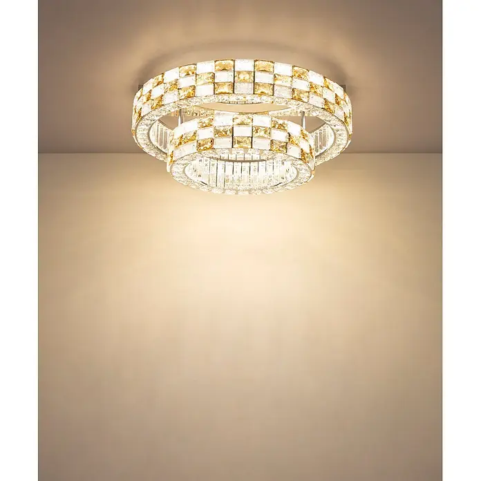 Globo LED-Deckenleuchte Lidia - 55 W - Zweistufige runde Kristall-Deckenleuchte mit klaren und bernsteinfarbenen Elementen, die eine Wand beleuchtet.